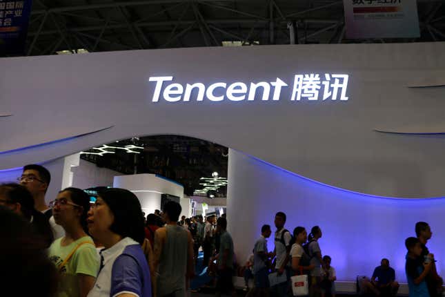 sign of Tencent in white letters on a wall above a lot of people