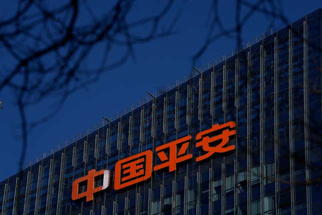 logo for Ping An Insurance Group is seen on a building, blurred branches are at the top of the photo, it is evening time